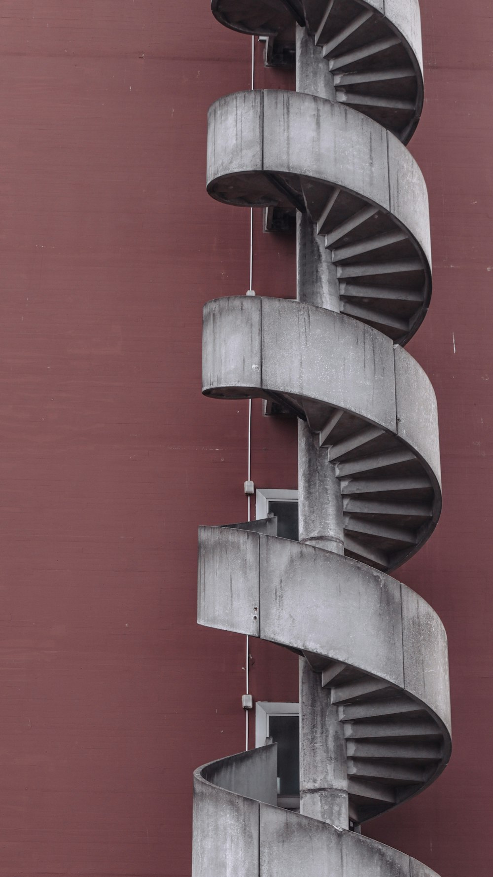 black spiral staircase on red wall