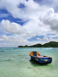 red and blue boat on sea under white clouds and blue sky during daytime