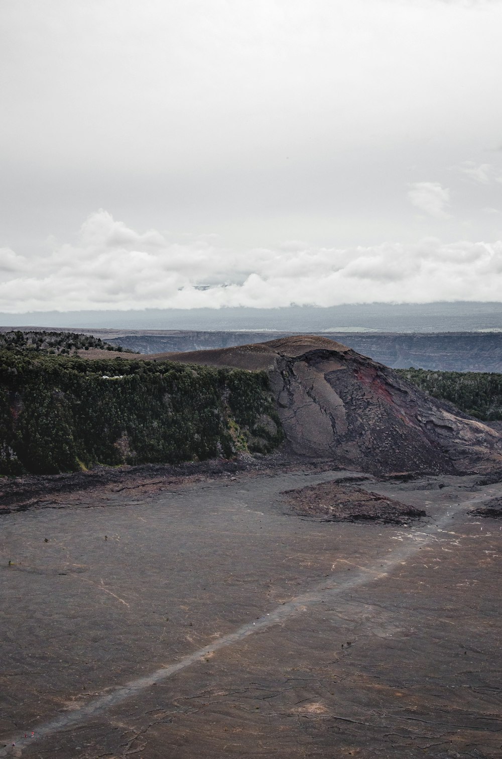 Brauner und grüner Berg am Meer unter weißen Wolken tagsüber