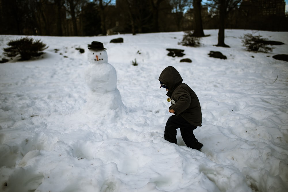 man in black jacket and black pants standing on snow covered ground during daytime