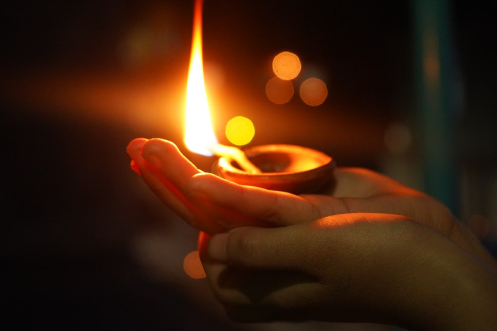 person holding lighted candle in close up photography