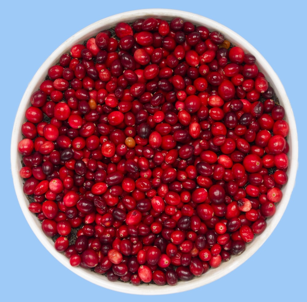 red round fruits on white ceramic bowl