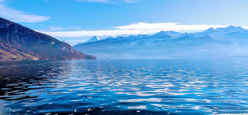 Cuerpo de agua cerca de la montaña bajo el cielo azul durante el día