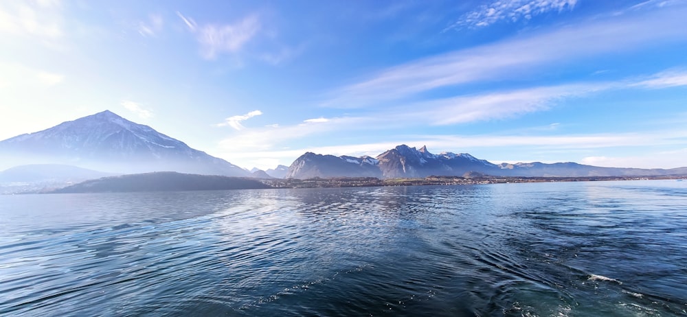 body of water near mountain under blue sky during daytime