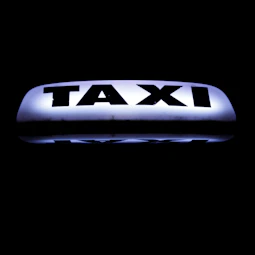 Close-up of the golden logo on the side door of a black taxi.