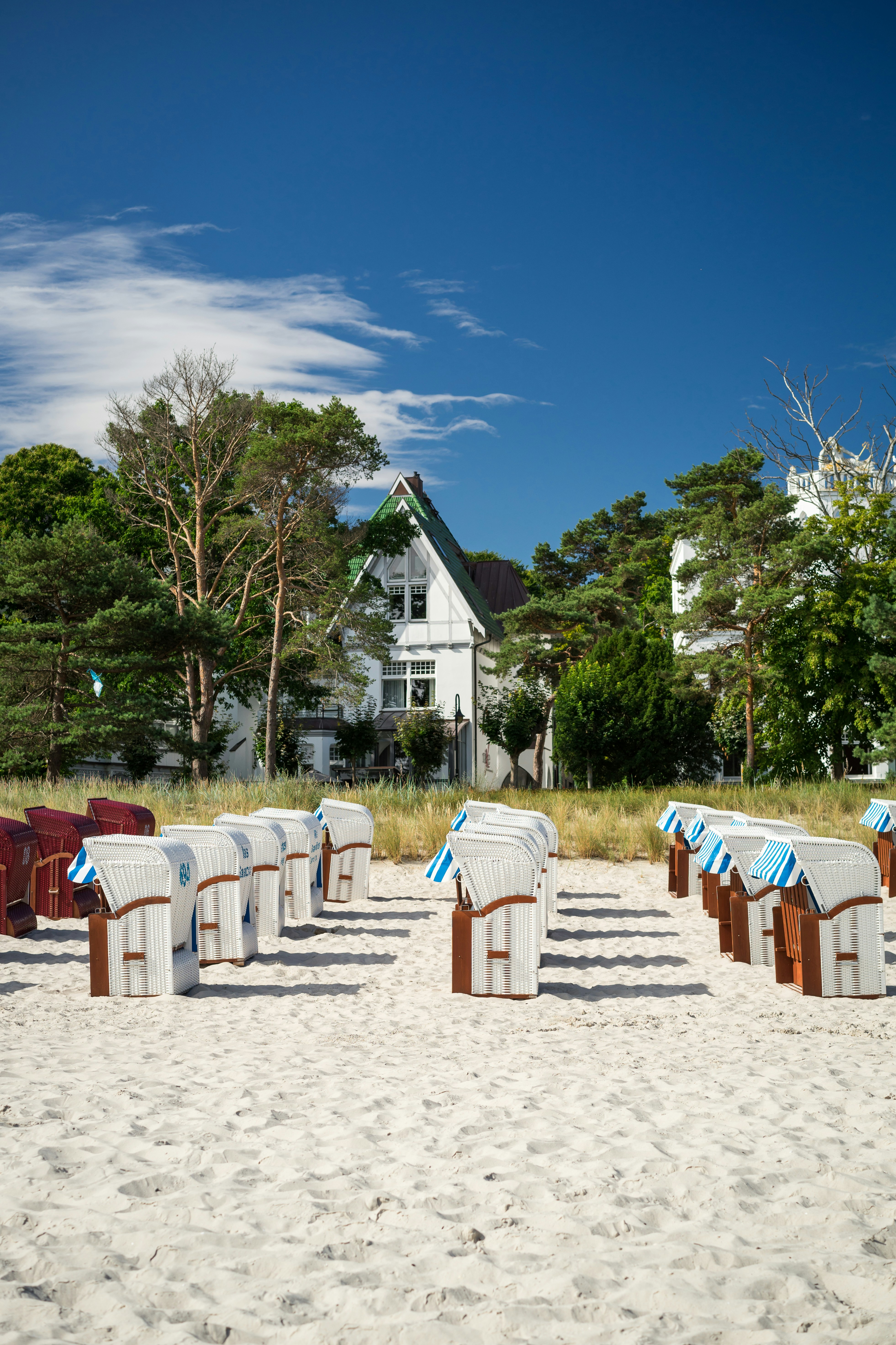 white and red wooden chairs and tables on white sand during daytime