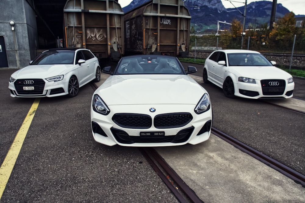 white bmw coupe parked beside white sedan