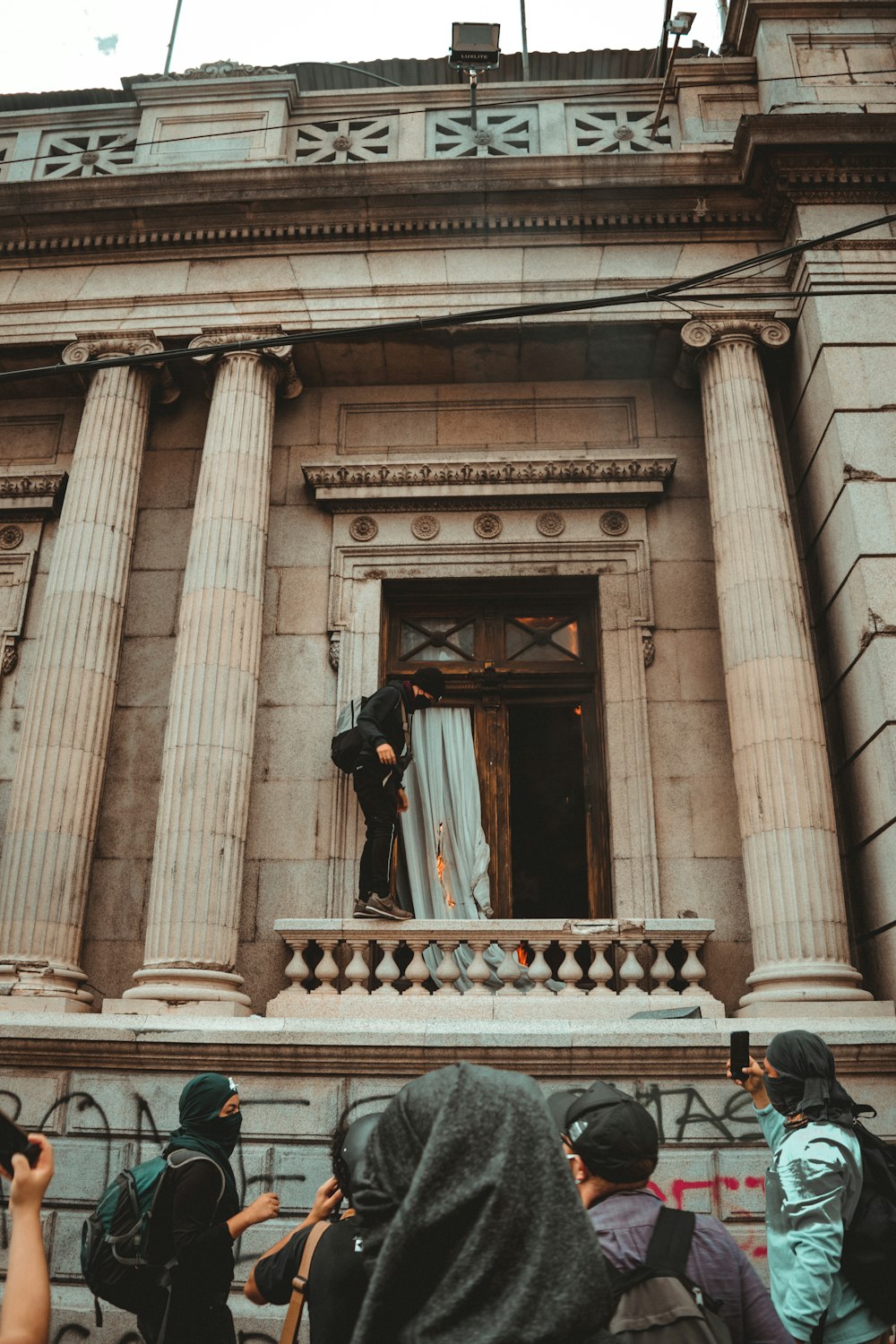 man in black jacket and black pants standing on brown concrete building during daytime