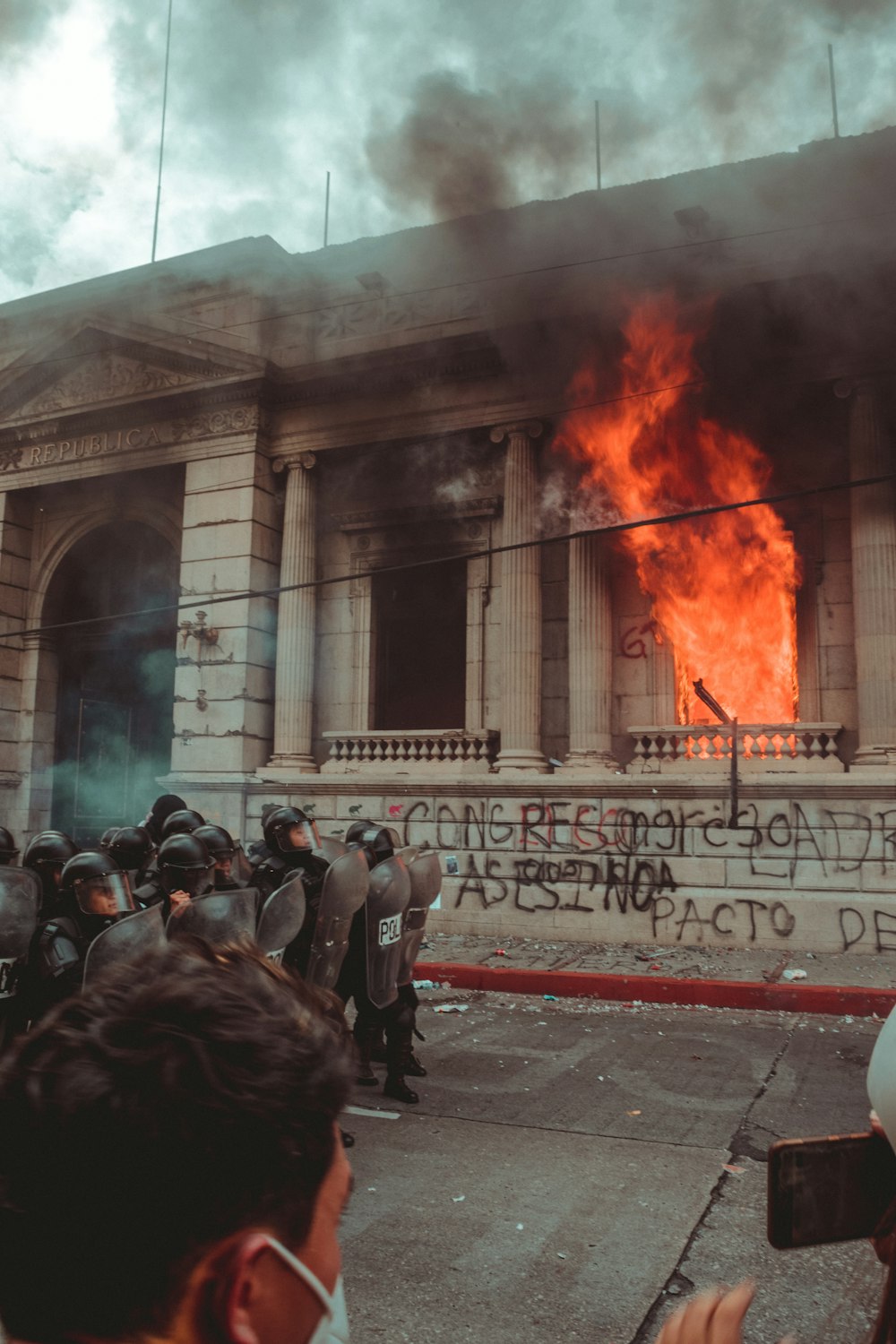 people standing in front of burning building during daytime