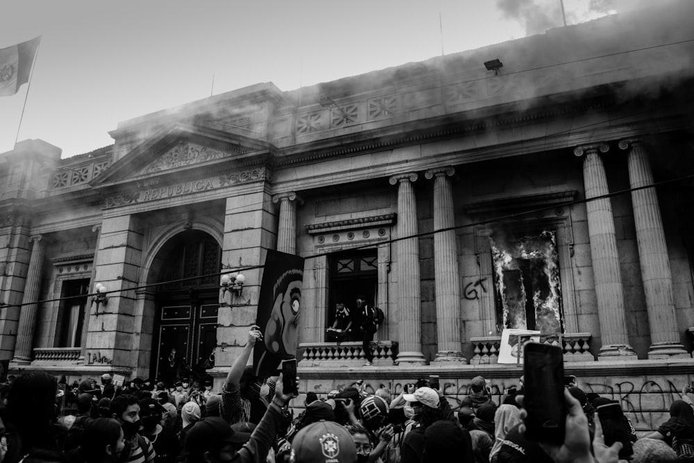 grayscale photo of people in front of building