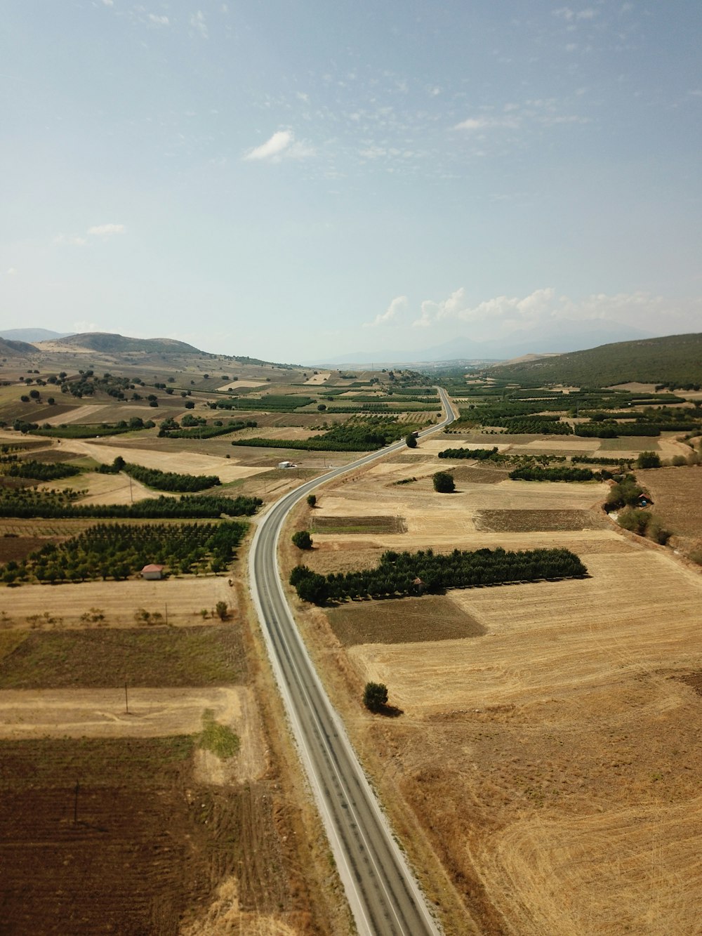 gray asphalt road in the middle of green grass field during daytime