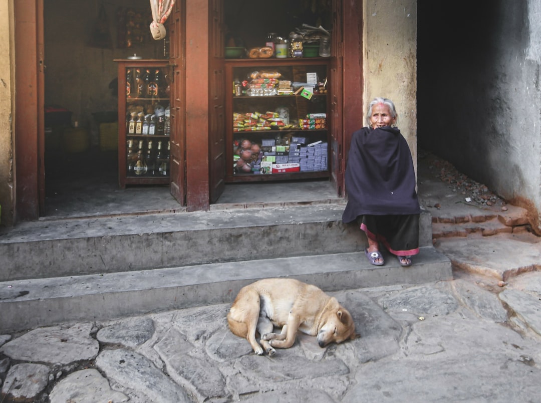 man in black robe sitting beside brown short coated dog