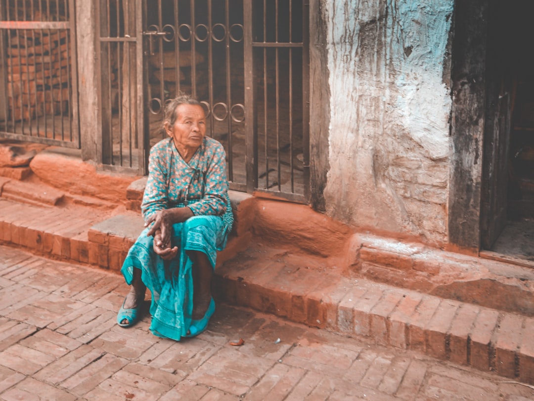 woman in blue and white dress sitting on brown concrete bench