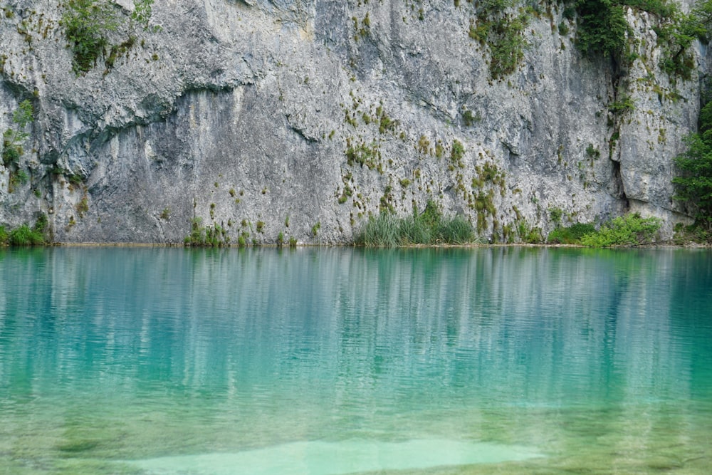 gray rocky mountain beside body of water during daytime