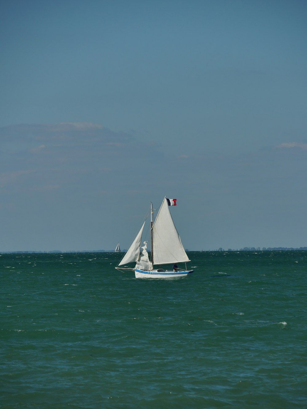 white sailboat on sea under gray sky
