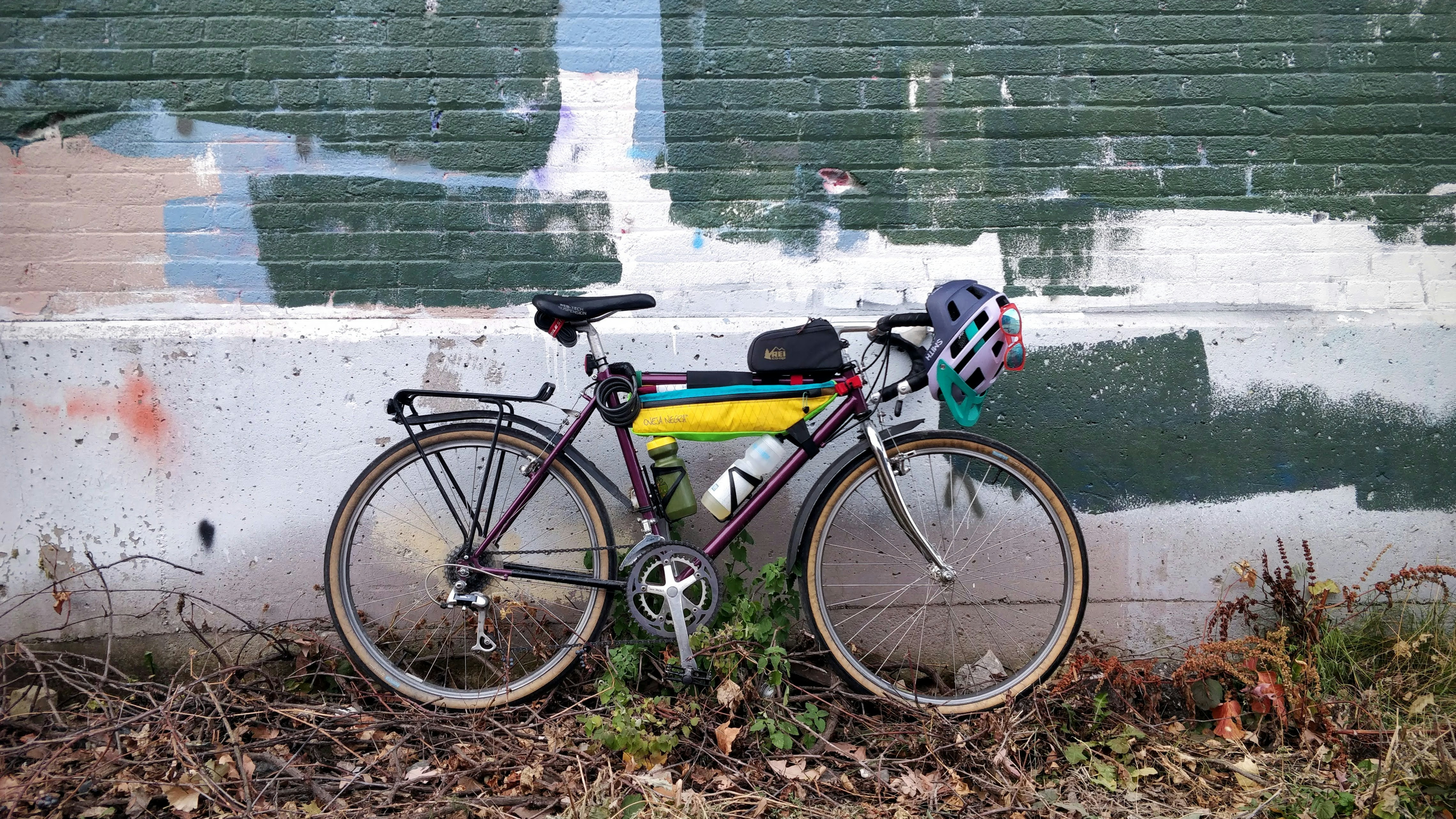 yellow and black road bike beside green wall