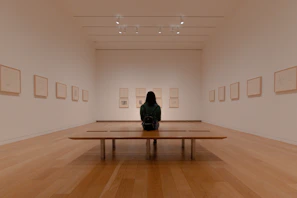man in black jacket sitting on brown wooden bench