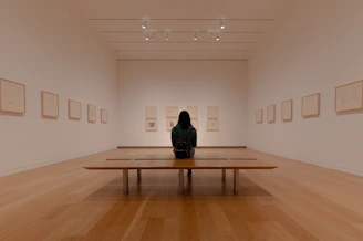 man in black jacket sitting on brown wooden bench