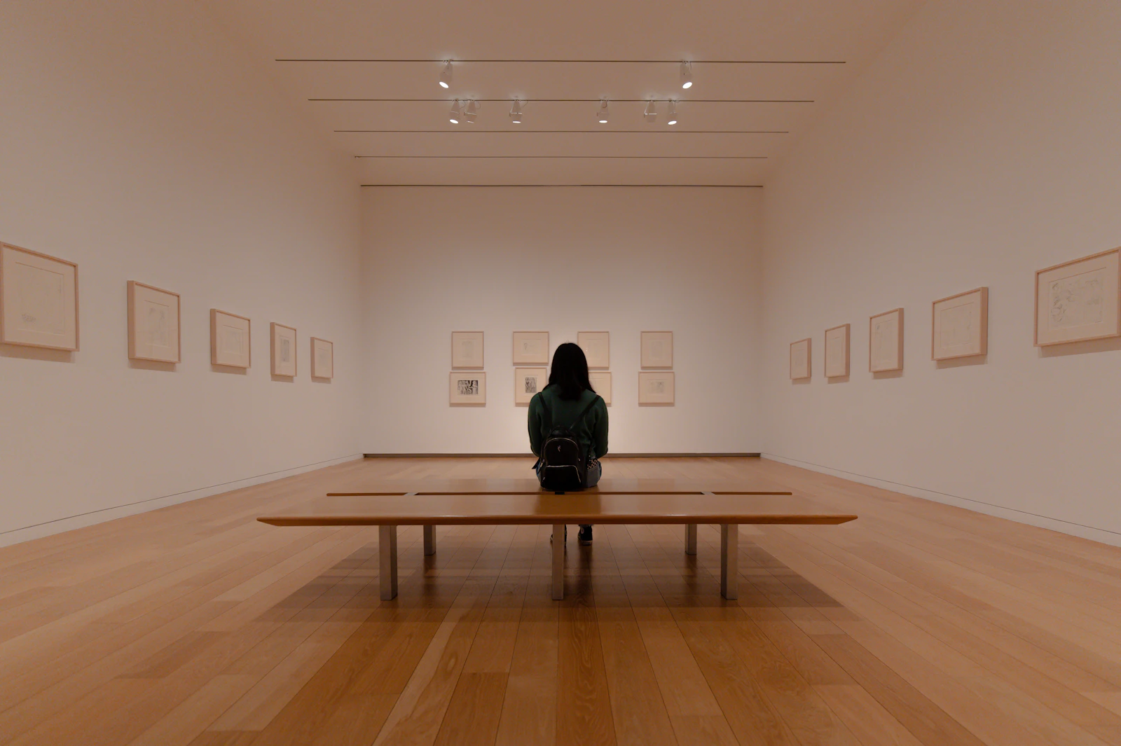 Man sitting on a wooden bench inside a gallery