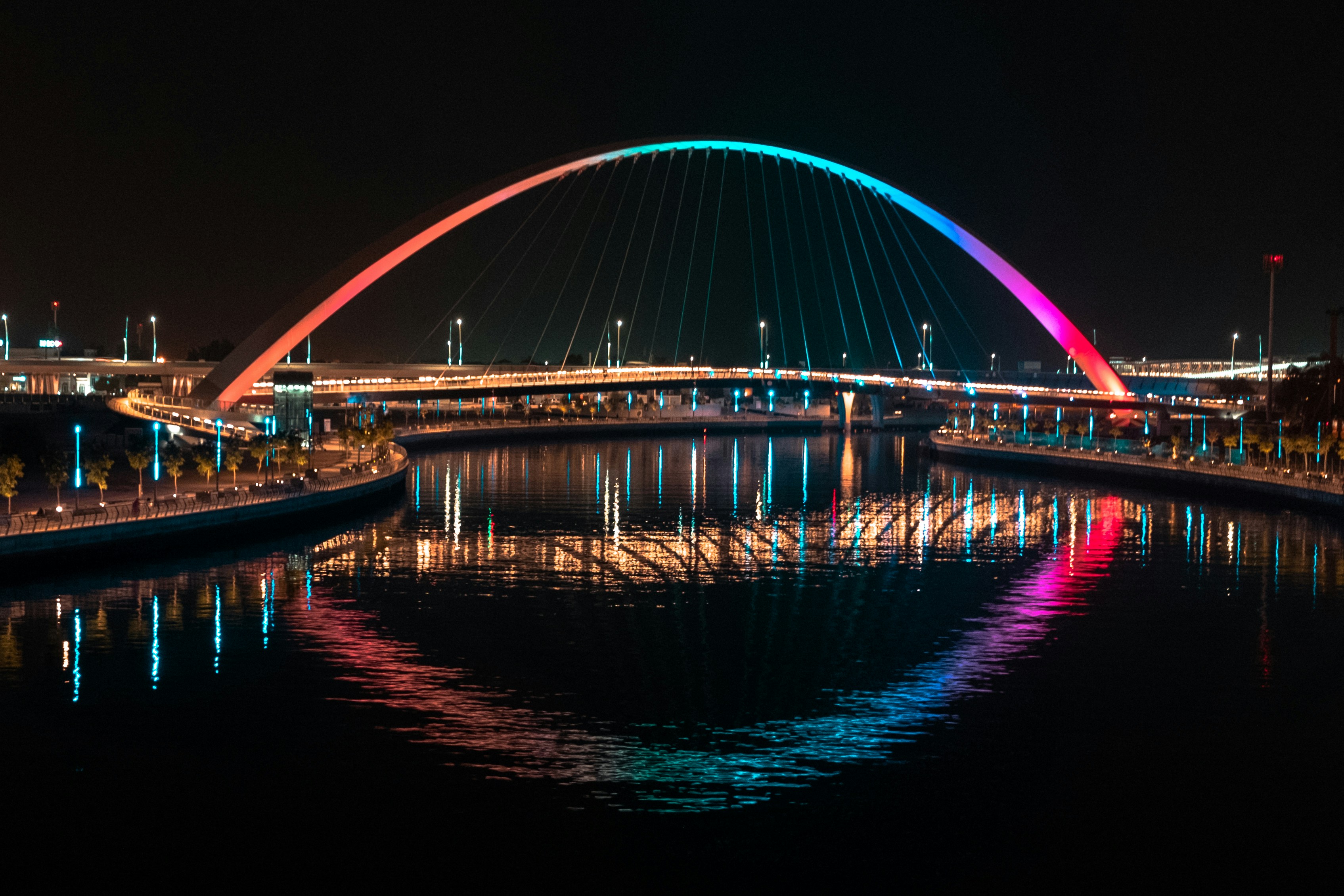 blue lighted bridge over water during night time