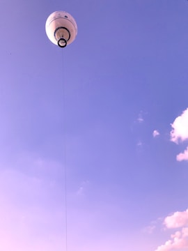 A high-altitude balloon floating against a clear blue stratospheric sky with scientific instruments attached.