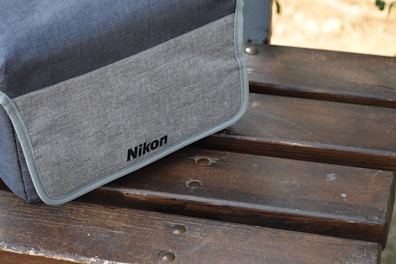 A sleek camera bag resting on a wooden bench, with compartments open showing organized camera gear.