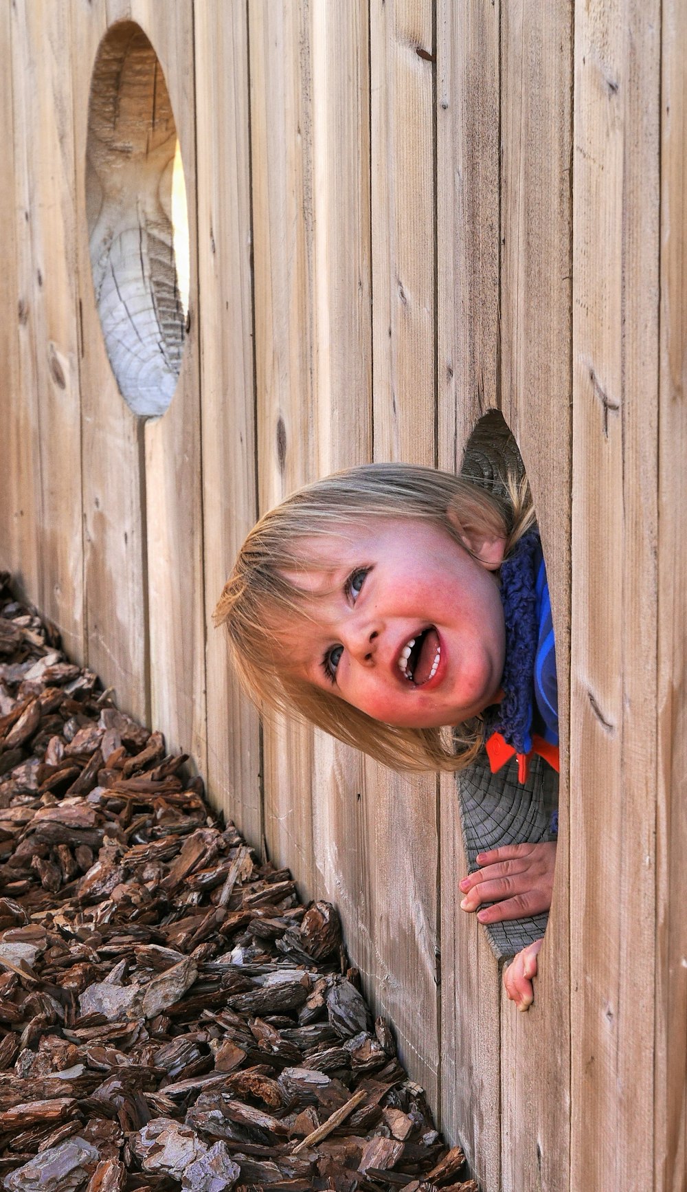 girl in blue denim jacket standing beside brown wooden fence