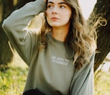woman in gray long sleeve shirt standing near brown tree during daytime