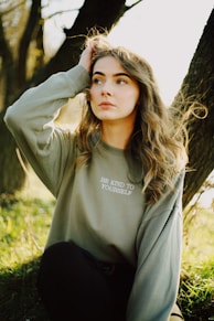 woman in gray long sleeve shirt standing near brown tree during daytime