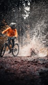 man in orange jacket riding on black mountain bike