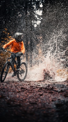 man in orange jacket riding on black mountain bike