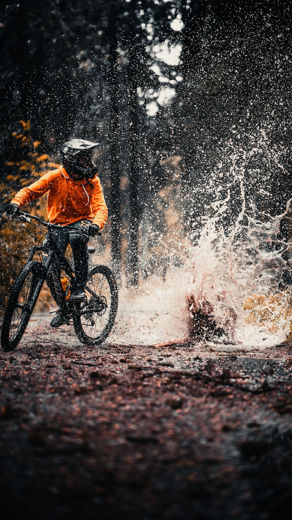 Hombre con chaqueta naranja montando en bicicleta de montaña negra