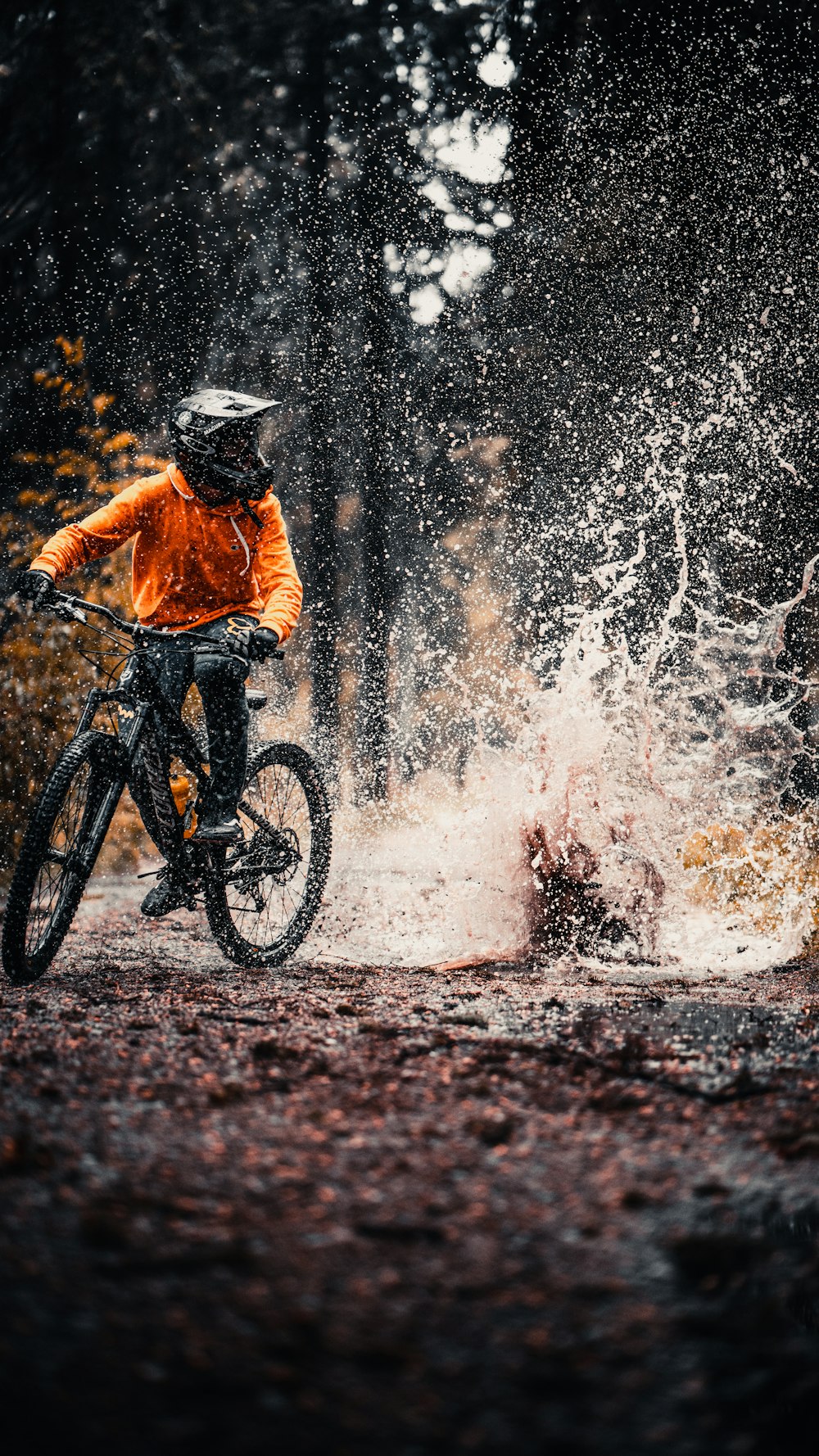 homme en veste orange sur un vélo de montagne noir