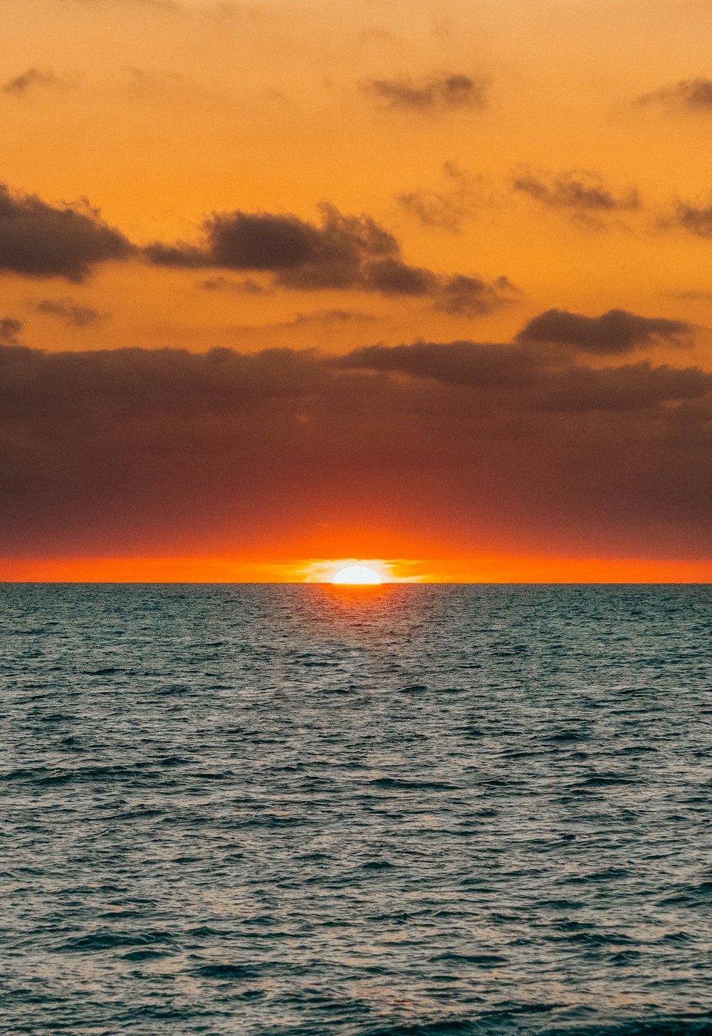 body of water under cloudy sky during sunset