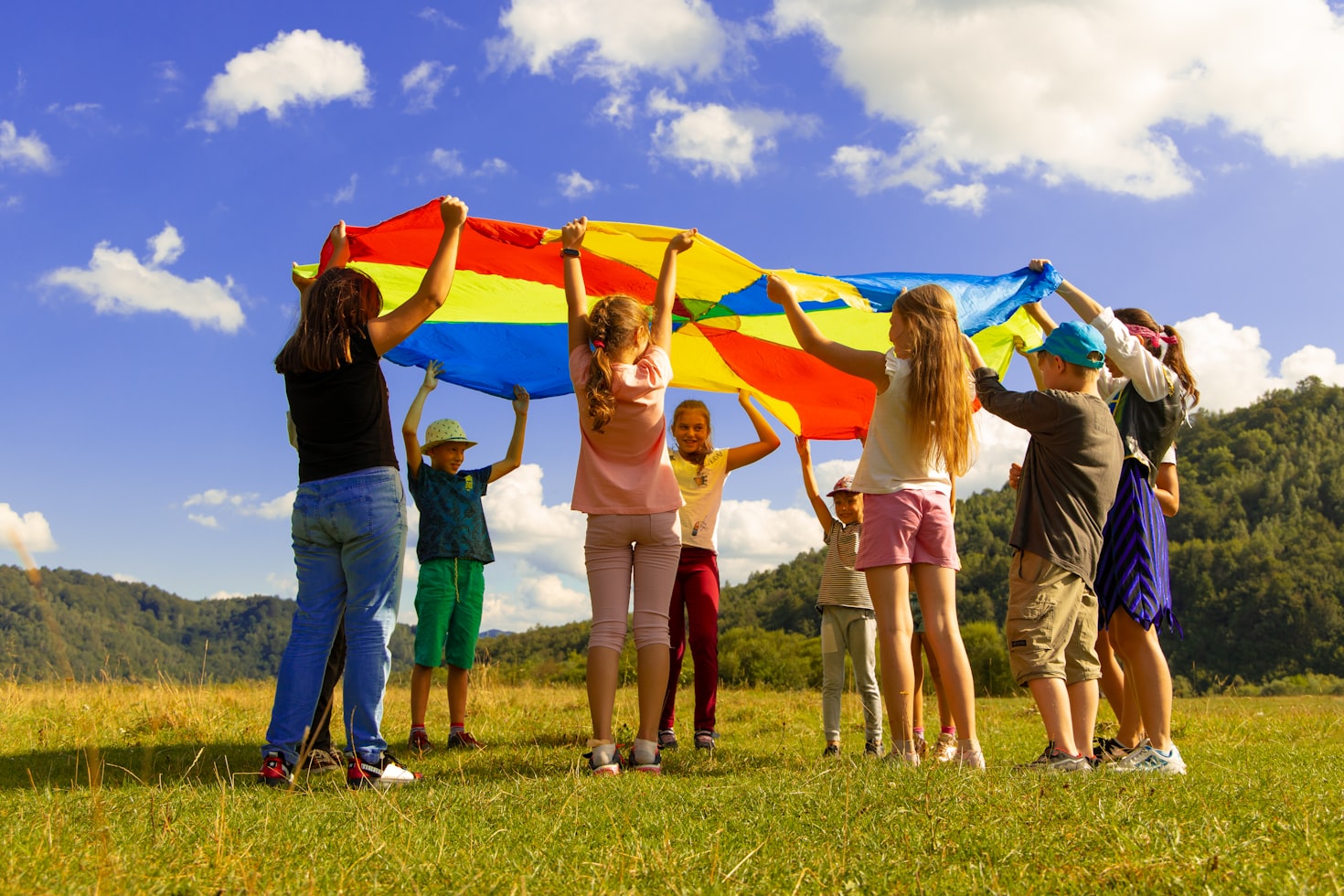children in a field playing with a parachute