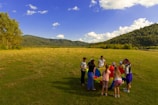 Children holding the colorful 5-meter parachute outdoors on a sunny day.