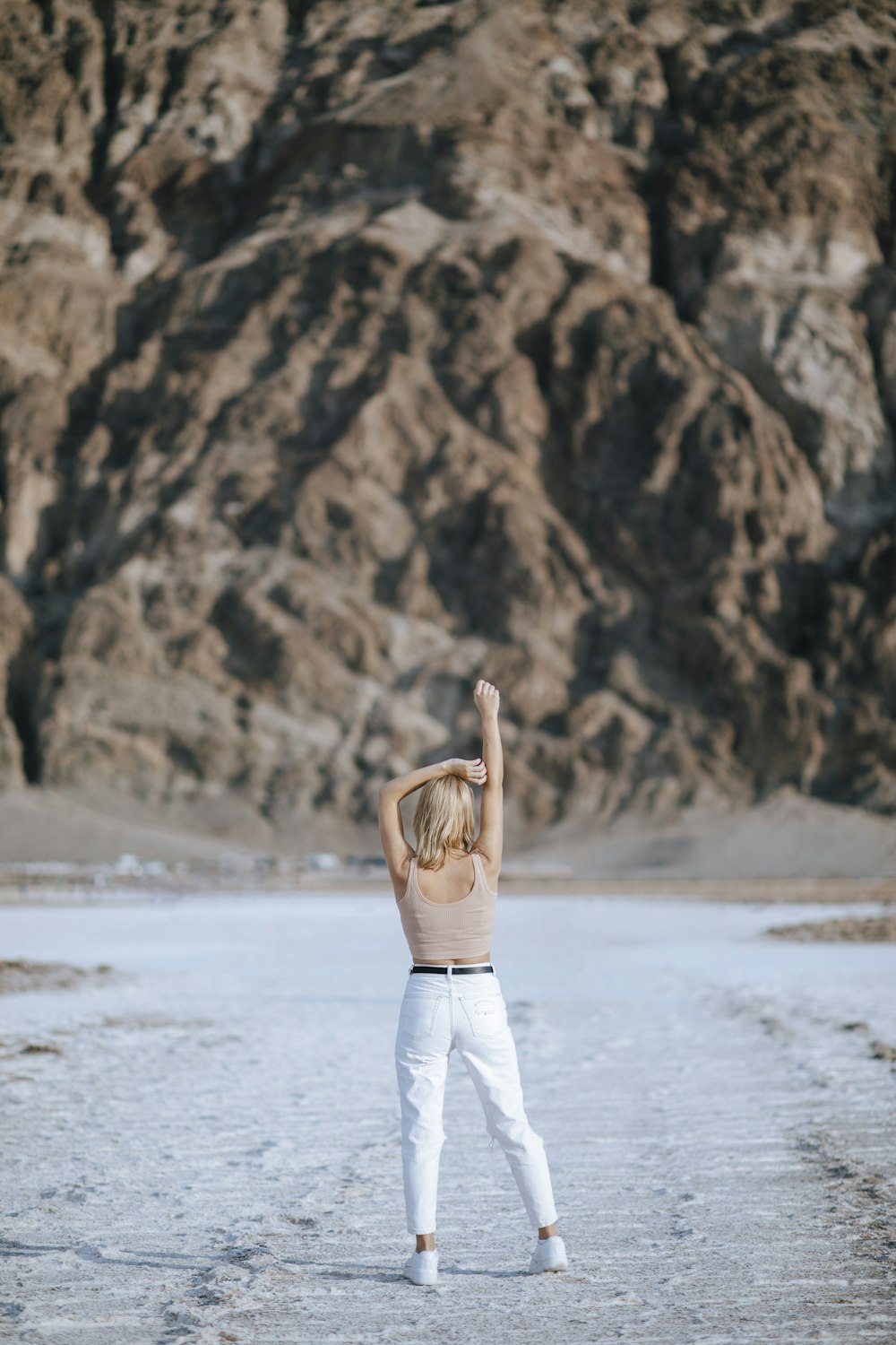 woman in brown long sleeve shirt and white pants standing on white snow covered ground during