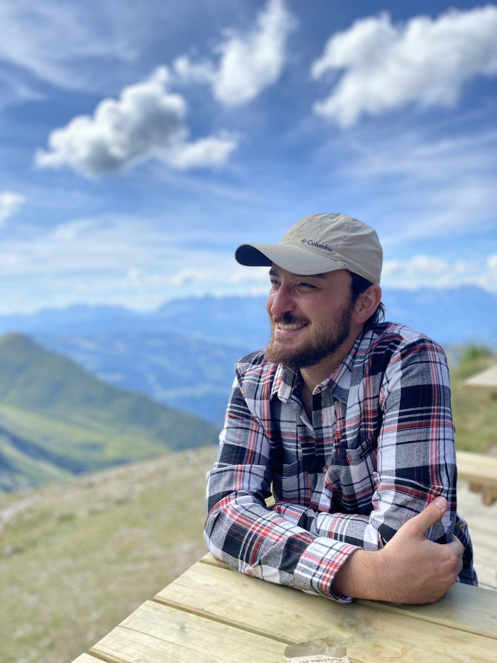 man in white hat and plaid shirt sitting on rock