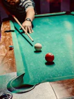 A hand chalking the tip of a billiard cue before a shot