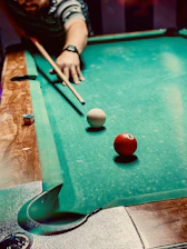 A student practicing shots while watching an online billiards tutorial on a tablet.
