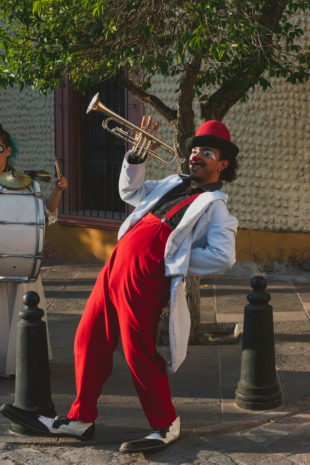 man in white dress shirt and red pants playing trumpet
