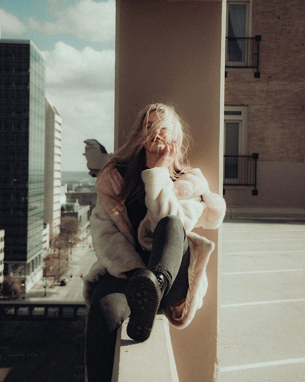 woman in beige coat sitting on brown concrete bench during daytime