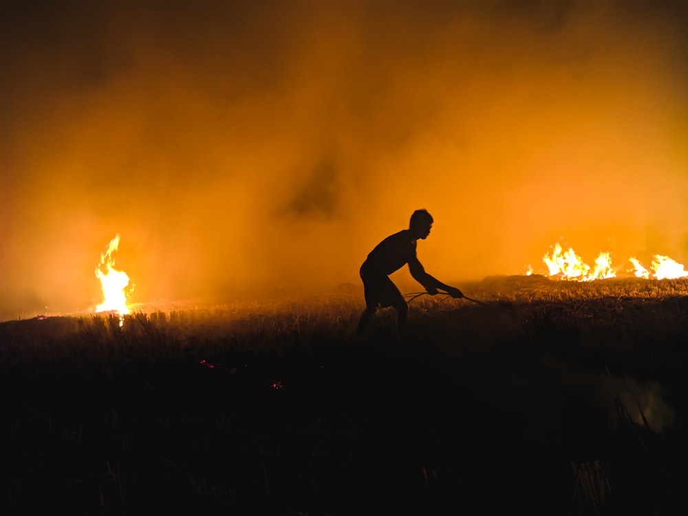 silhueta do homem que caminha no campo de grama durante o pôr do sol