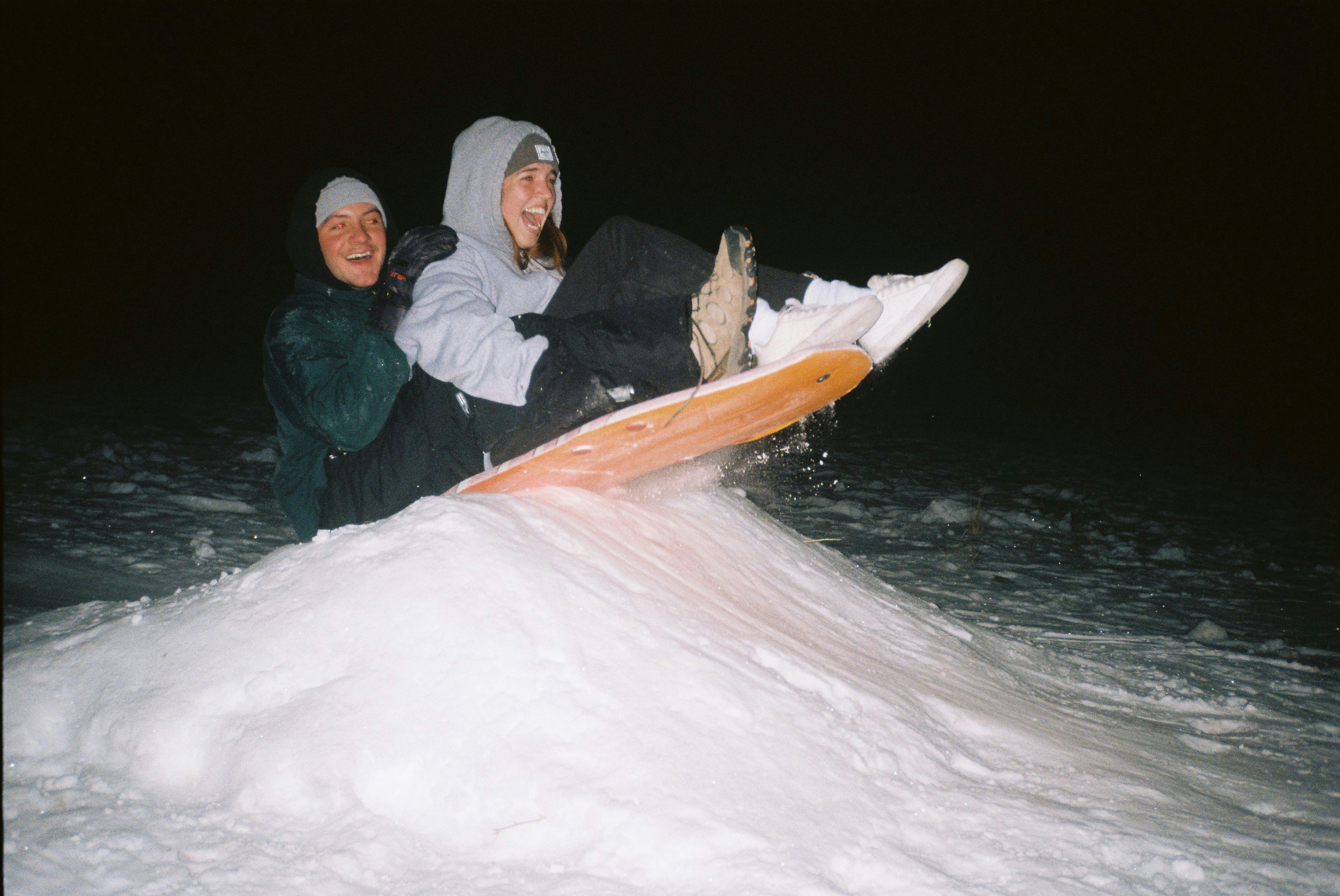 man and woman sitting on snow covered ground during daytime, 