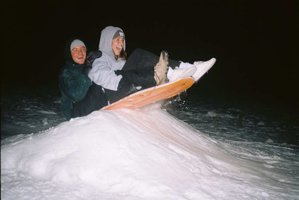 man and woman sitting on snow covered ground during daytime