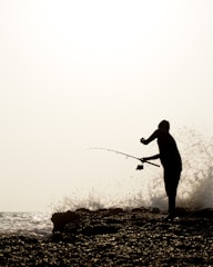 silhouette of man fishing on sea during daytime