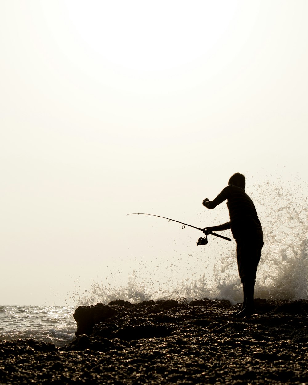 silhouette of man fishing on sea during daytime