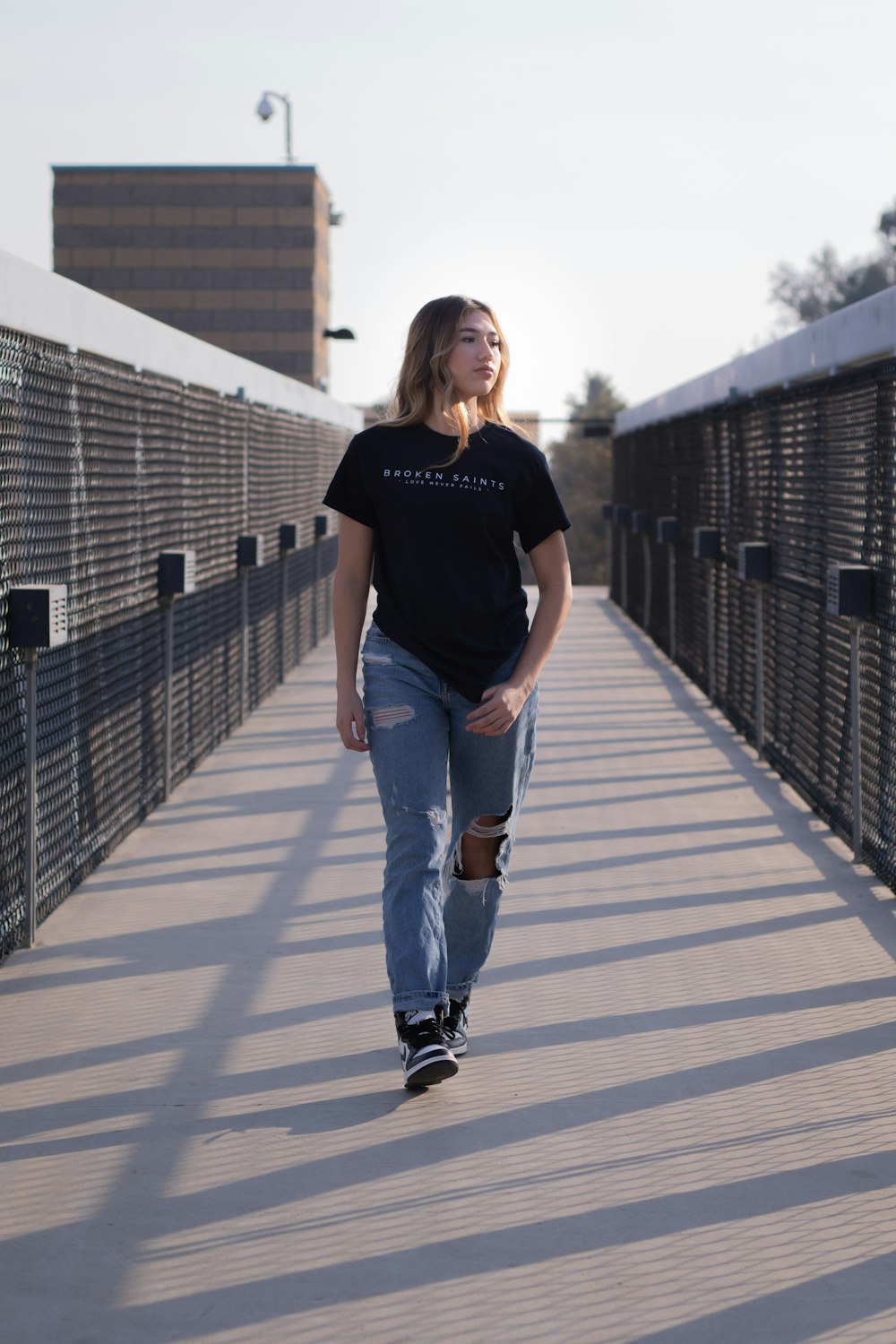 woman in black crew neck t-shirt and blue denim jeans standing on white wooden bridge