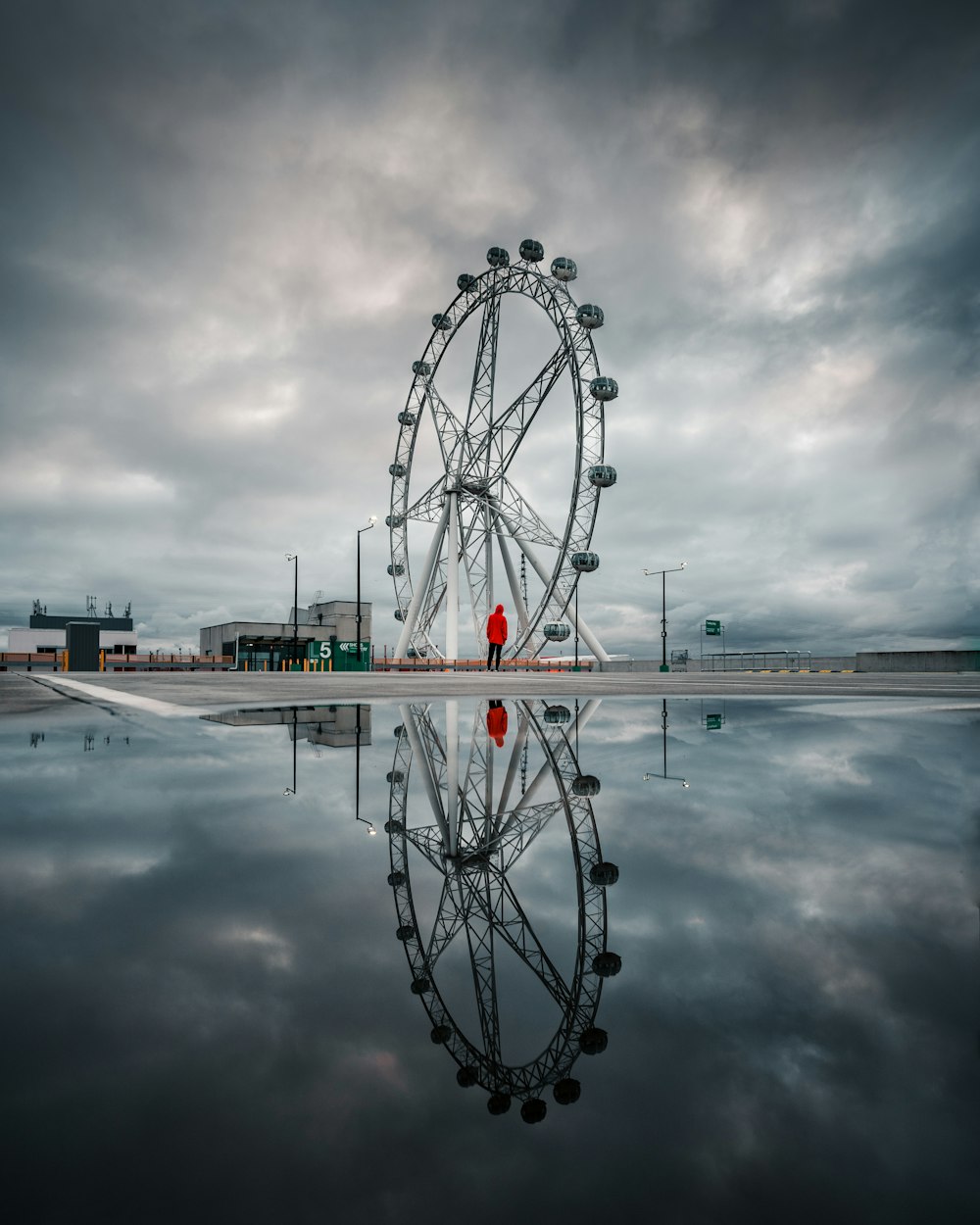 ferris wheel near body of water under cloudy sky during daytime