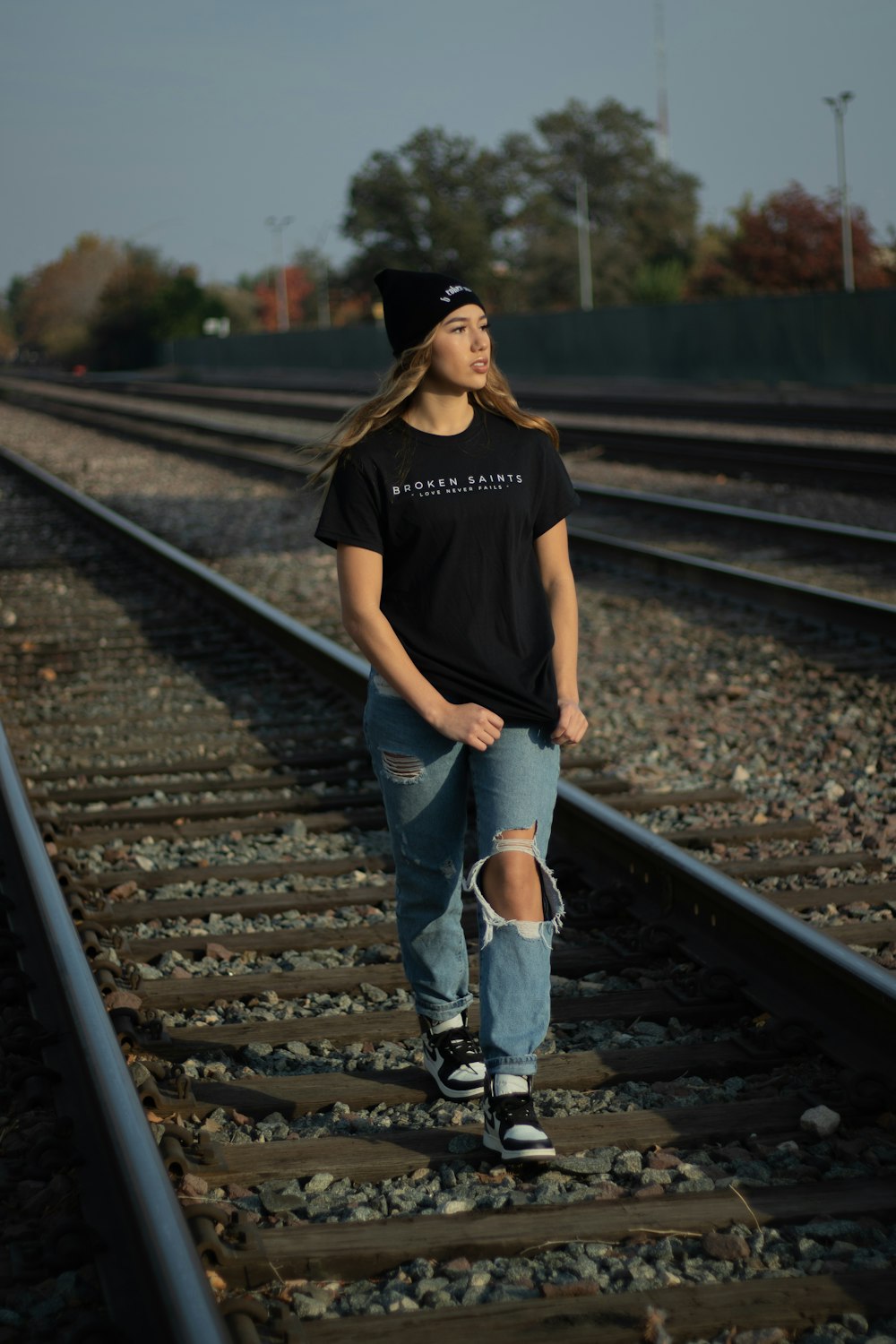 man in black crew neck t-shirt and blue denim jeans standing on train rail during